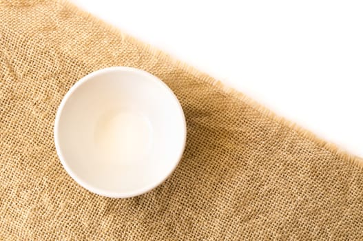 Closeup top view empty white bowl on sackcloth and white background texture, food concept