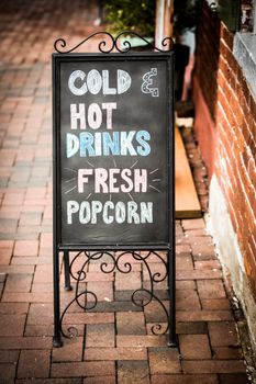 A vintage black chalkboard with Cold Hot Drinks and Fresh Popcorn written on the front.