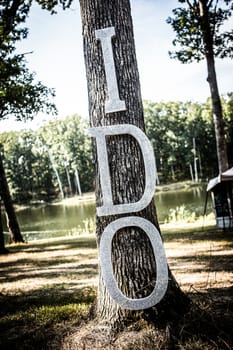 Homemade blinged out wedding sign hanging on a tree.