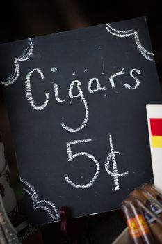 Simple black chalkboard sign offering cigars.