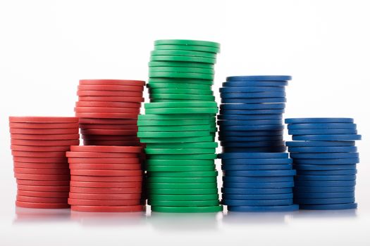 Red, green, blue plastic poker chips from the side on white with reflection.