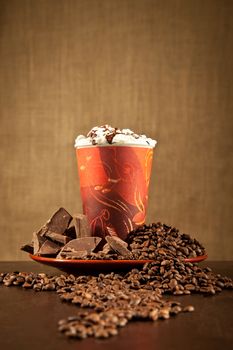 Hot coffee or cappuccino drink with bars of chocolate and coffee beans using an artistic composition.