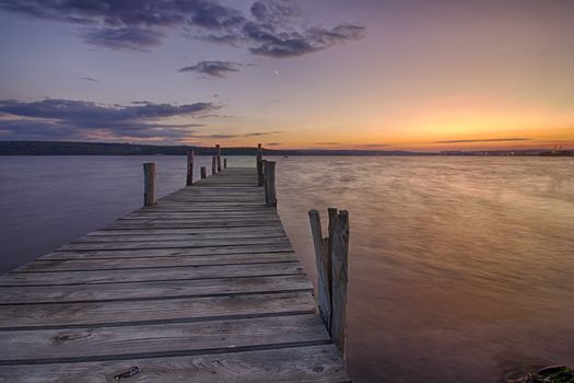 Beauty and calm sunset on lake with wooden pier 