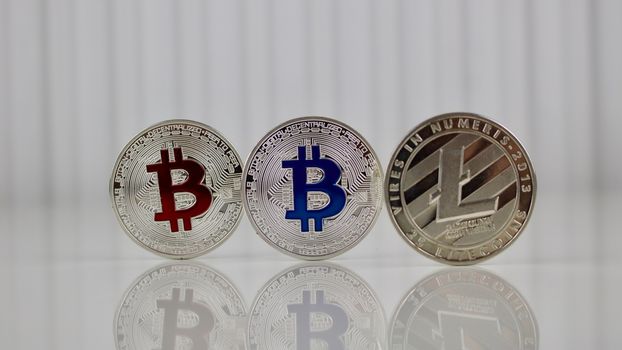 Digital currency physical red and blue bitcoin coins and silver litecoin.