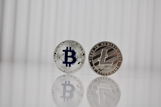 Digital currency physical silver bitcoin and litecoin coins on white table.