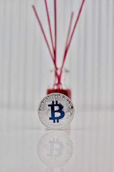 Digital currency physical silver bitcoin coin with blue sign near fragrance.
