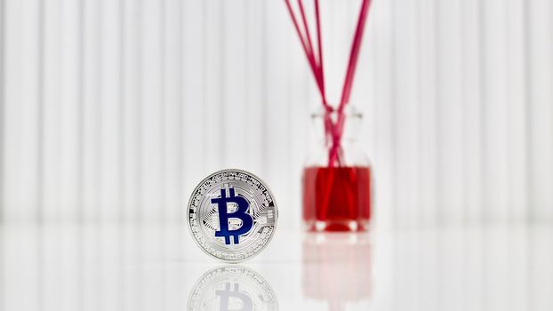Digital currency physical blue bitcoin coin near red fragrance