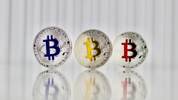 Digital currency physical silver colorful bitcoins on white table.