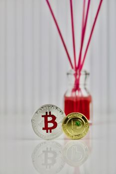 Digital currency physical silver bitcoin and gold peercoin near red bottle.
