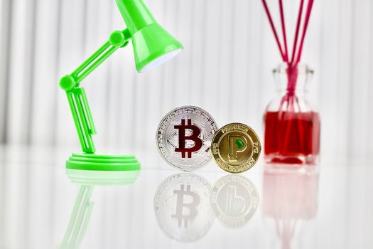 Digital currency physical silver bitcoin and gold peercoin coin near lamp