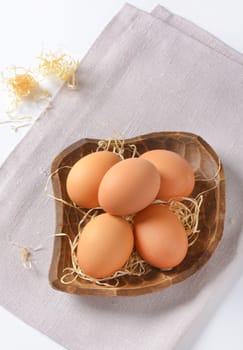 bowl of brown eggs and straw