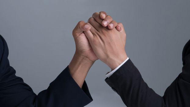 businessman engaged in arm wrestling  on gray background