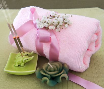 a pink towel, incense sticks and candle