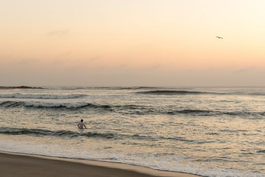 A tourist swimming in the Atlantic Ocean after sunset at Cape Cross on the Skeleton Coast of Namibia