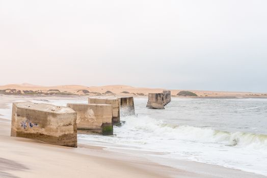 Pillars of the old railroad bridge over the mouth of the Swakop River at Swakopmund in the Namib Desert on the Atlantic Coast of Namibia