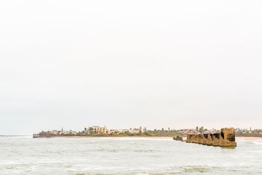 Pillars of the old railroad bridge over the mouth Swakop River with part of Swakopmund in the back