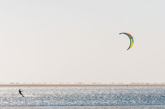 The silhouette of a kite surfer on the lagoon at Walvis Bay in the Namib Desert on the Atlantic Coast of Namibia