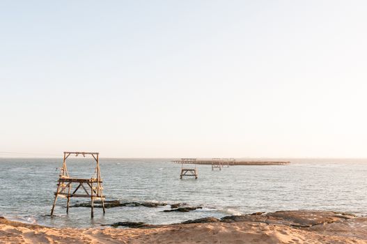 A guano island at sunset with a cableway connecting it to the mainland near Longbeach in the Namib Desert on the Atlantic Coast of Namibia