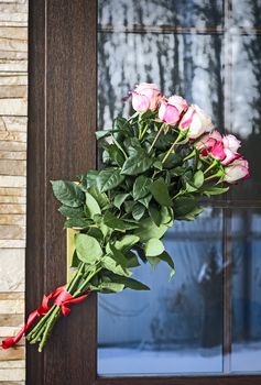 A beautiful bouquet of roses as a gift attached to the door handle.