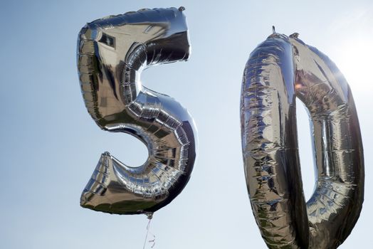 silver balloons for a 50th anniversary floating among the clouds