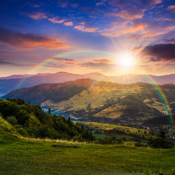 composite summer  landscape. view from hillside to village near forest in high mountains in sunset light