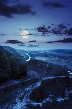 view to village in vally from stone wall of an old ruined castle in the mountains at night in full moon light