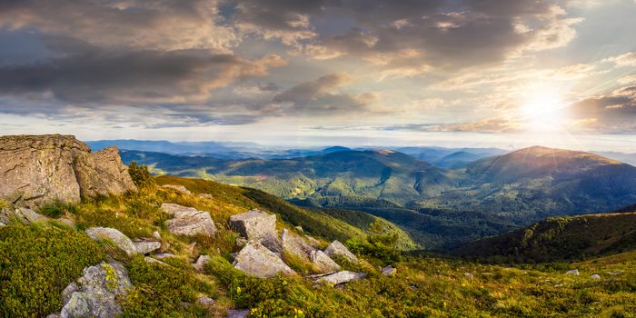 panoranic mountain landscape. valley with stones in grass on top of the hillside of mountain range in sunset light