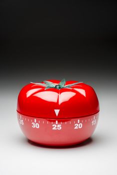 Tomato-shaped kitchen timer set at 25 minutes to fight procrastination in studying and working.