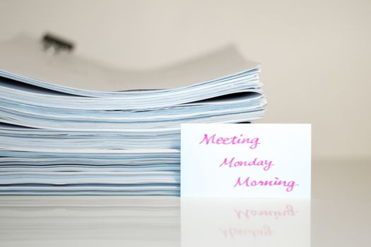 Meeting Monday Morning; Stack of Documents on white desk and Background.