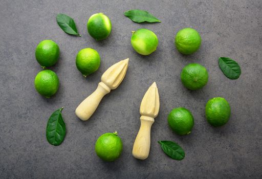 Fresh limes and wooden juicer on dark stone background. Top view