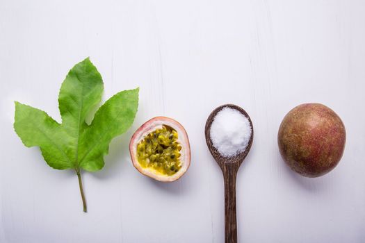 Passion fruit and leave with salt in wooden spoon on wooden white background.
