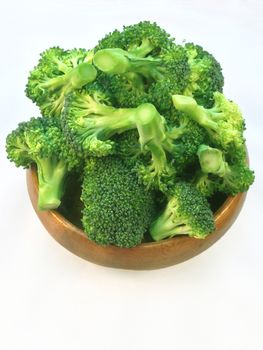 Broccoli in wooden bowl and wooden spoon on white background