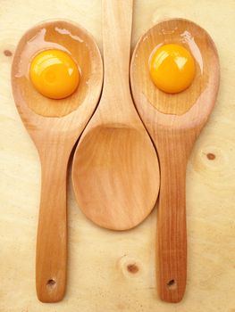 Eggs on wooden spoon on wooden background