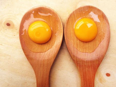 Eggs on wooden spoon on wooden background