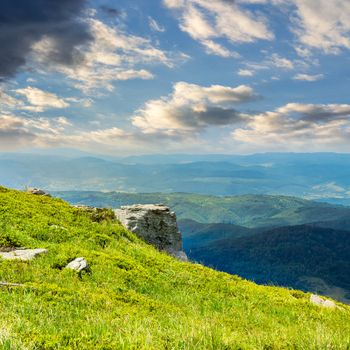 view on high mountains from hillside covered with grass with few stones on the edge