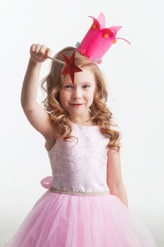 Little fairy girl in pink dress and crown with magic wand putting spell, isolated on white background