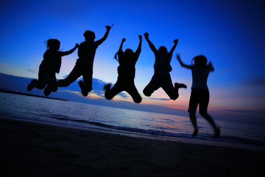 Silhouette of young friends jumping on the Pattaya beach and  backdrop of sunset over the sea in Thailand