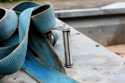 Detail of metal buckle on a blue strong industrial load strap, on a metal trailer