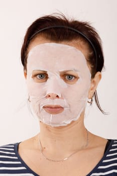 ordinary middle-aged housewife woman with cosmetic sheet mask on her face