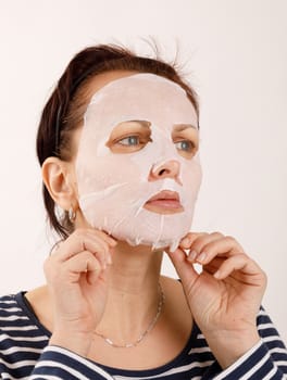 ordinary middle-aged housewife woman with cosmetic sheet mask on her face