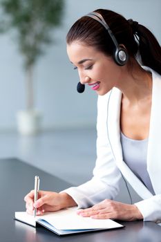 Smiling businesswoman or helpdesk operator with headset in an office