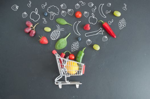Grocery shopping cart filled with fruits and vegetables and sketches on a chalkboard