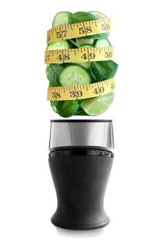 Fresh green fruits and vegetables above a blender with tape measure