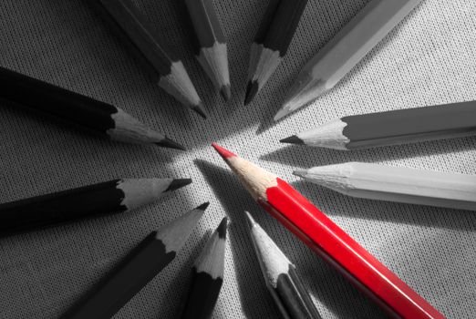 Red pencil standing out in a group of black and white pencils