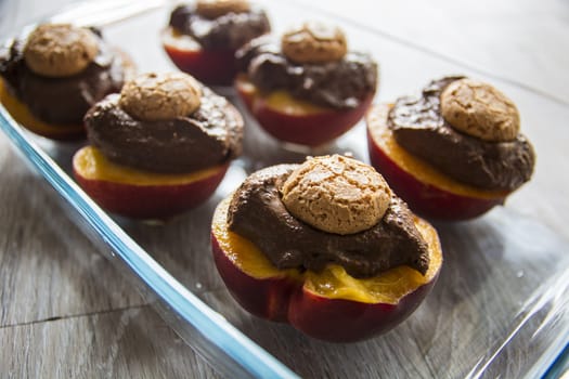 Close-up shot of delicious peaches cooked with chocolate and cookies and served on plate.