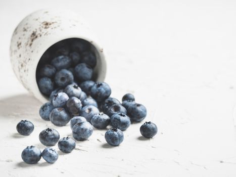 Blueberries on white concrete background. Blueberry border design. Fresh picked bilberries scattered close up. Copyspace. Closeup