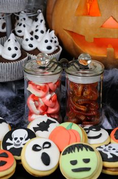Jelly candies in the form of jaws and worms in a jar on a Halloween table among other sweets