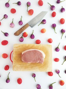 Pork on cutting board with tomatoes and  Thai eggplants