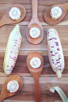 White and purple corn with rice wooden ladle on wooden background