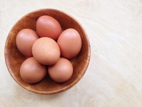 Eggs in wooden bowl on wooden background